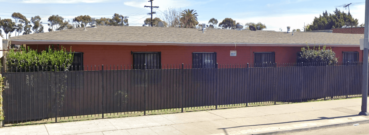 A red building with a black fence in front.